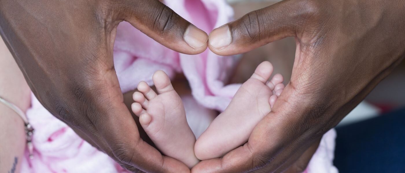 Hands positioned in the shape of a heart holding baby feet